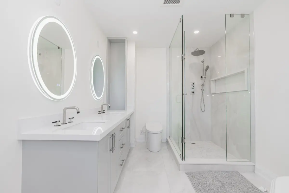 A finished bathroom: round mirrors, a double vanity and a glass shower (photograph supplied by the client)