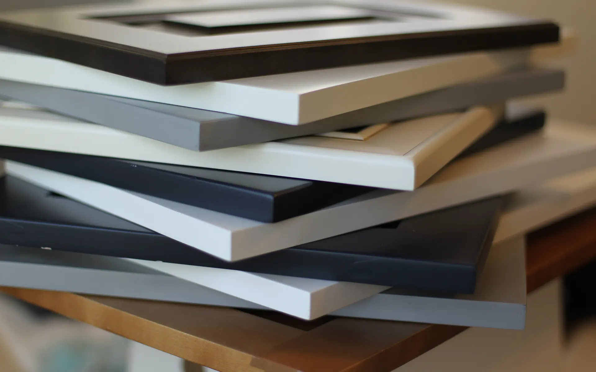 A stack of cabinet-door samples in black, white, grey and navy, each with its own edge profile