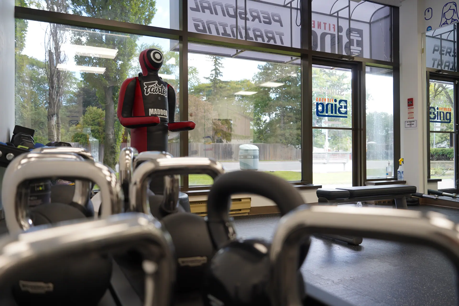Inside Bing Fitness: kettlebells in the foreground, “Personal Training” and the Bing Fitness logo on the windows