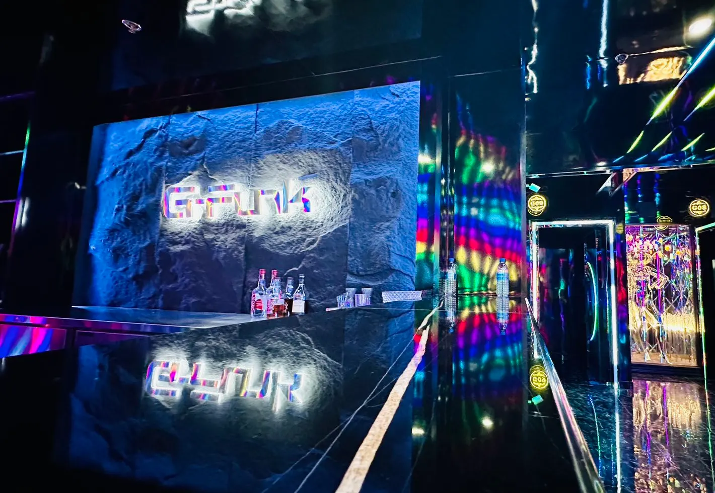 G-Funk’s reception: the lit wordmark on a rock-faced wall, a mirrored corridor and coloured light