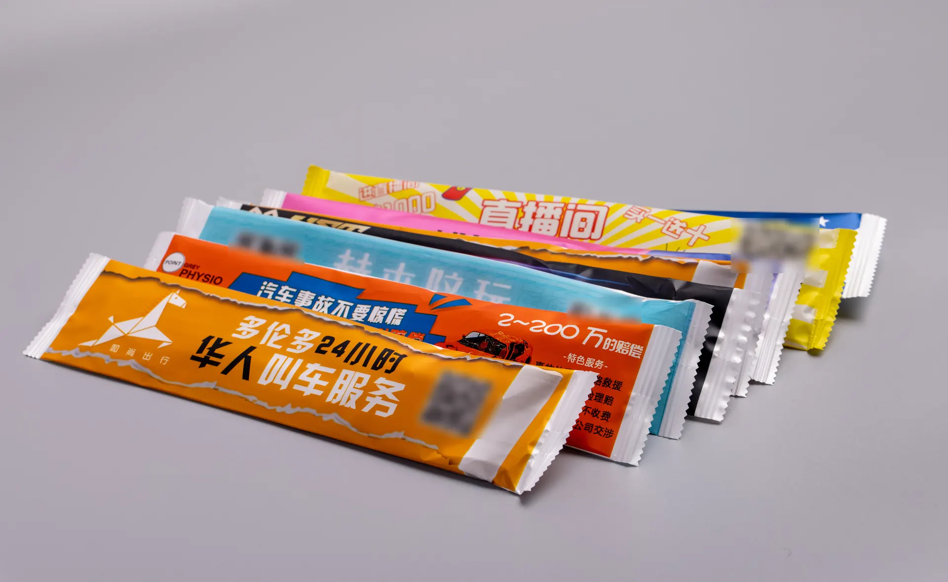 A stack of ad-printed takeaway cutlery wraps (QR codes blurred)
