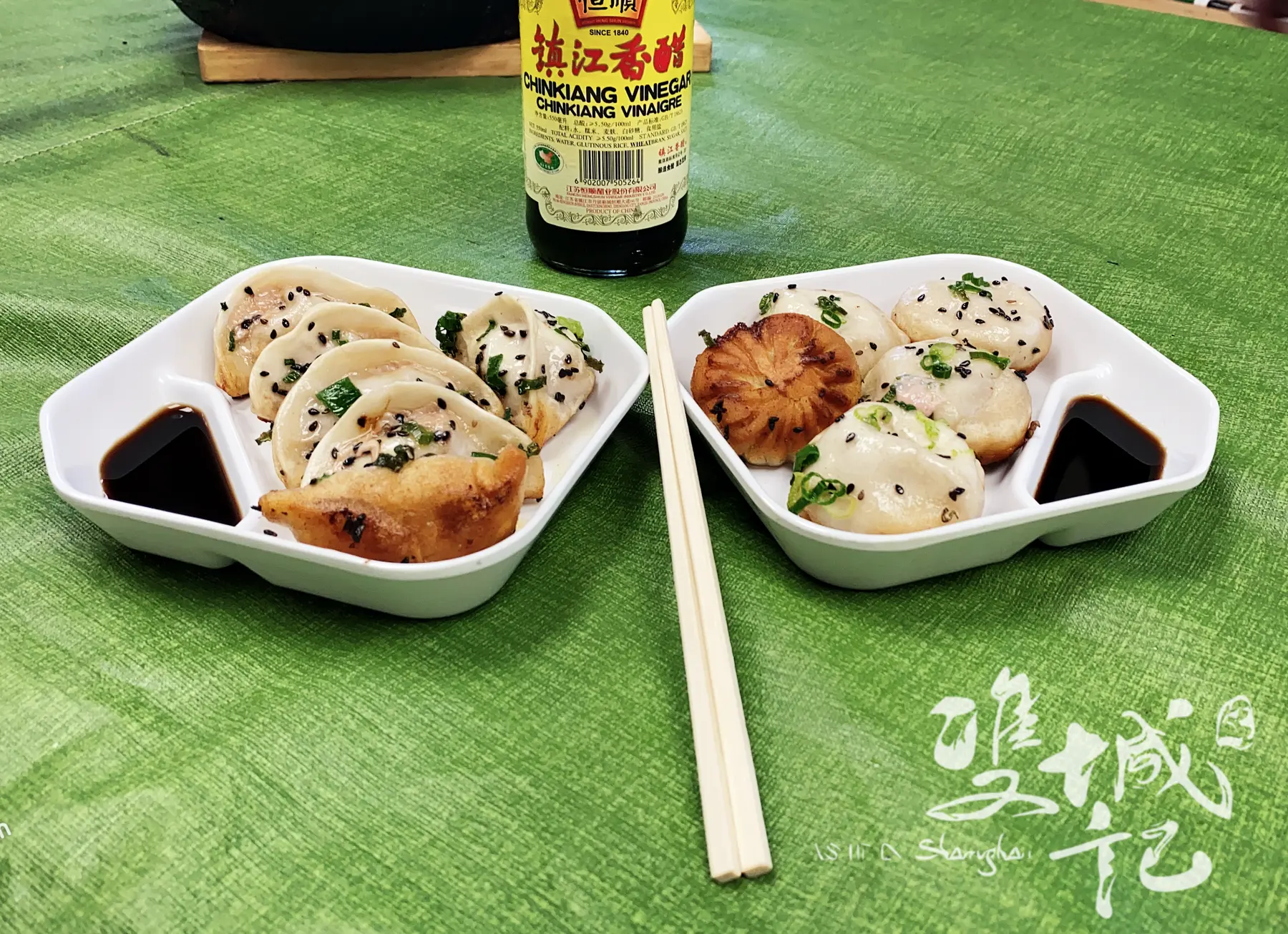 两盘生煎与锅贴放在绿色桌布上，右下角用白色「双城记」毛笔字署名（餐厅拍摄）