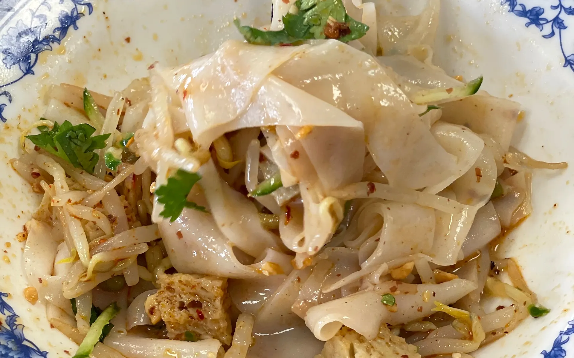 Liangpi in a blue-and-white bowl, chopsticks lifting a bite