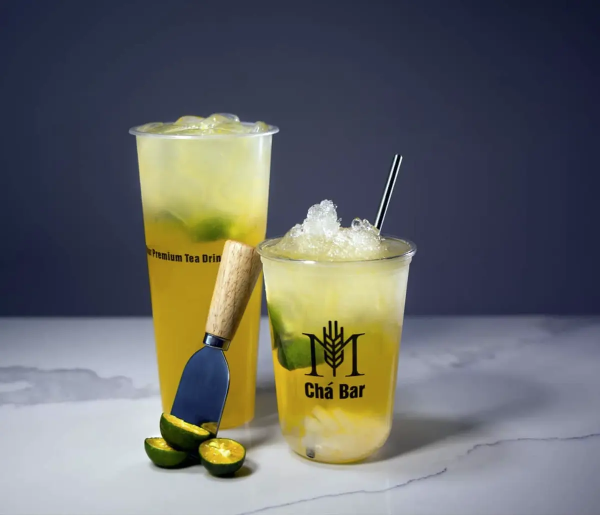Two citrus fruit teas, the M Chá Bar mark printed in one colour on the cup