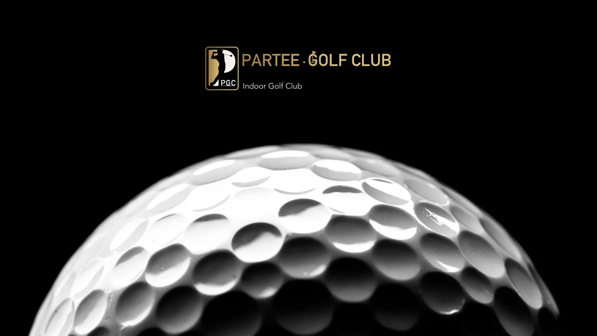 The top of a golf ball on black, light catching its dimples, the gold Partee Golf Club signature above