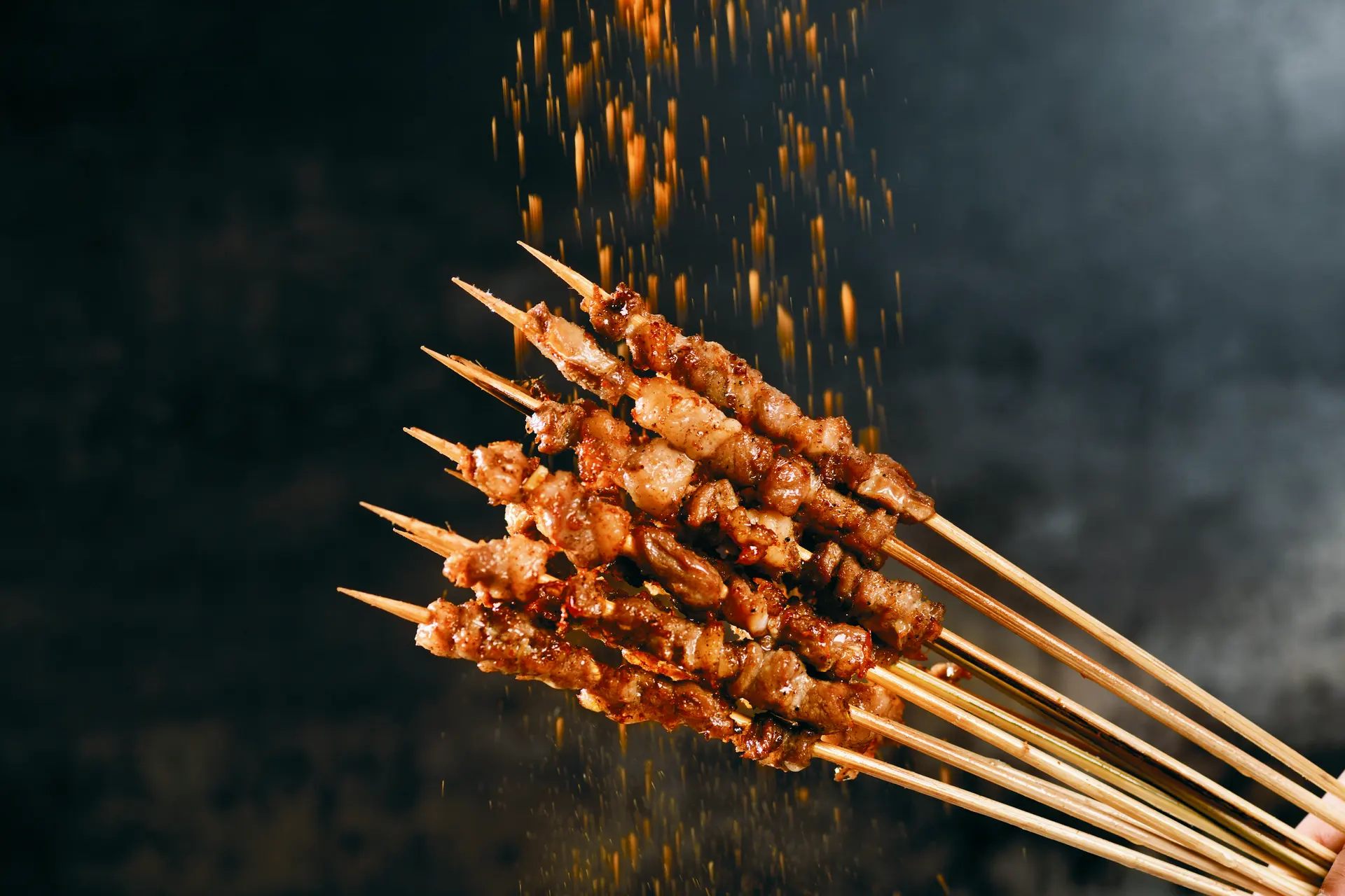 A handful of beef belly skewers under falling sparks