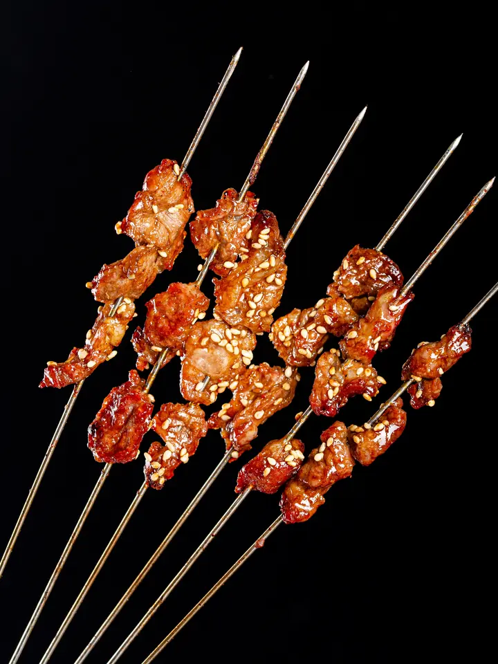 Poster: “Skewers with music, drinks with stories” over beef skewers on black