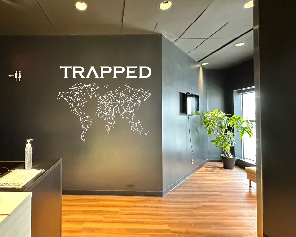 Wall two: a faceted, line-drawn world map under the TRAPPED wordmark (preview)